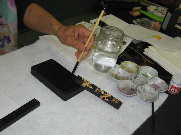 An ink stick was ground into the ink stone. The artist prepares her brush for another drawing.