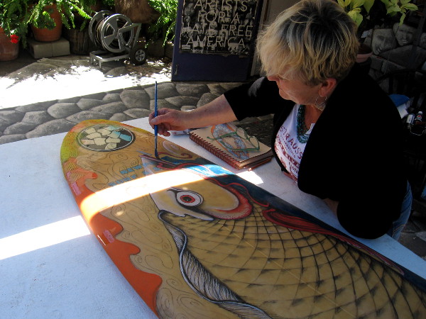 Friendly local artist paints a surfboard on the table outside Studio 10.